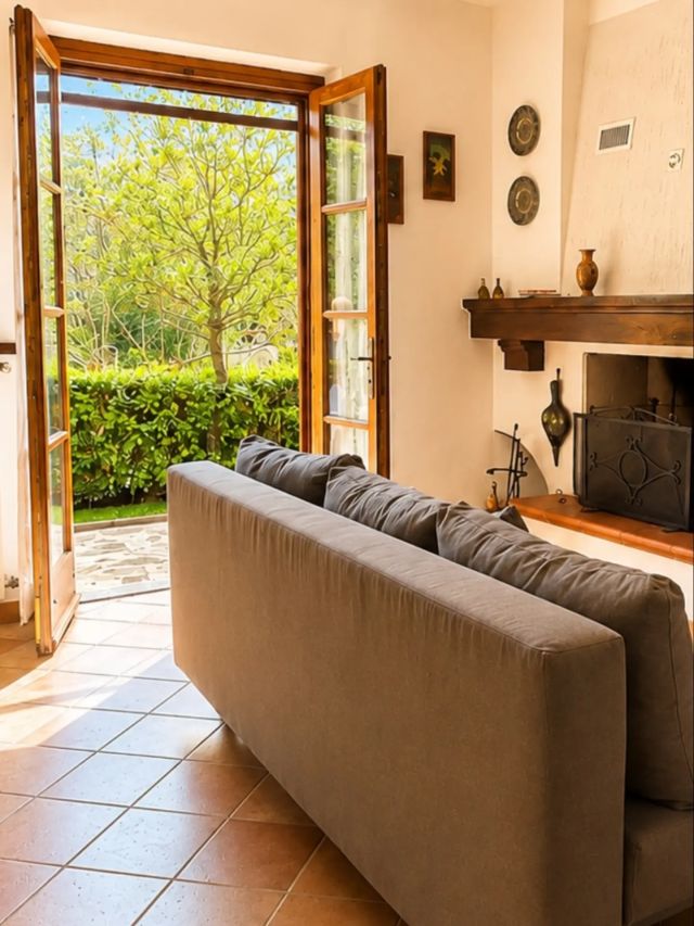 Il camino, il divano e le porte aperte sul giardino. – Villa Marisa, casa vacanze in Versilia